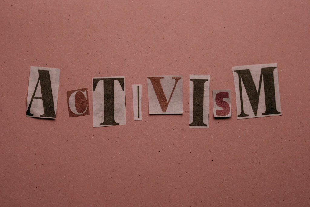 Paper cutouts spelling 'Activism' on a pink surface, emphasizing social movement themes.