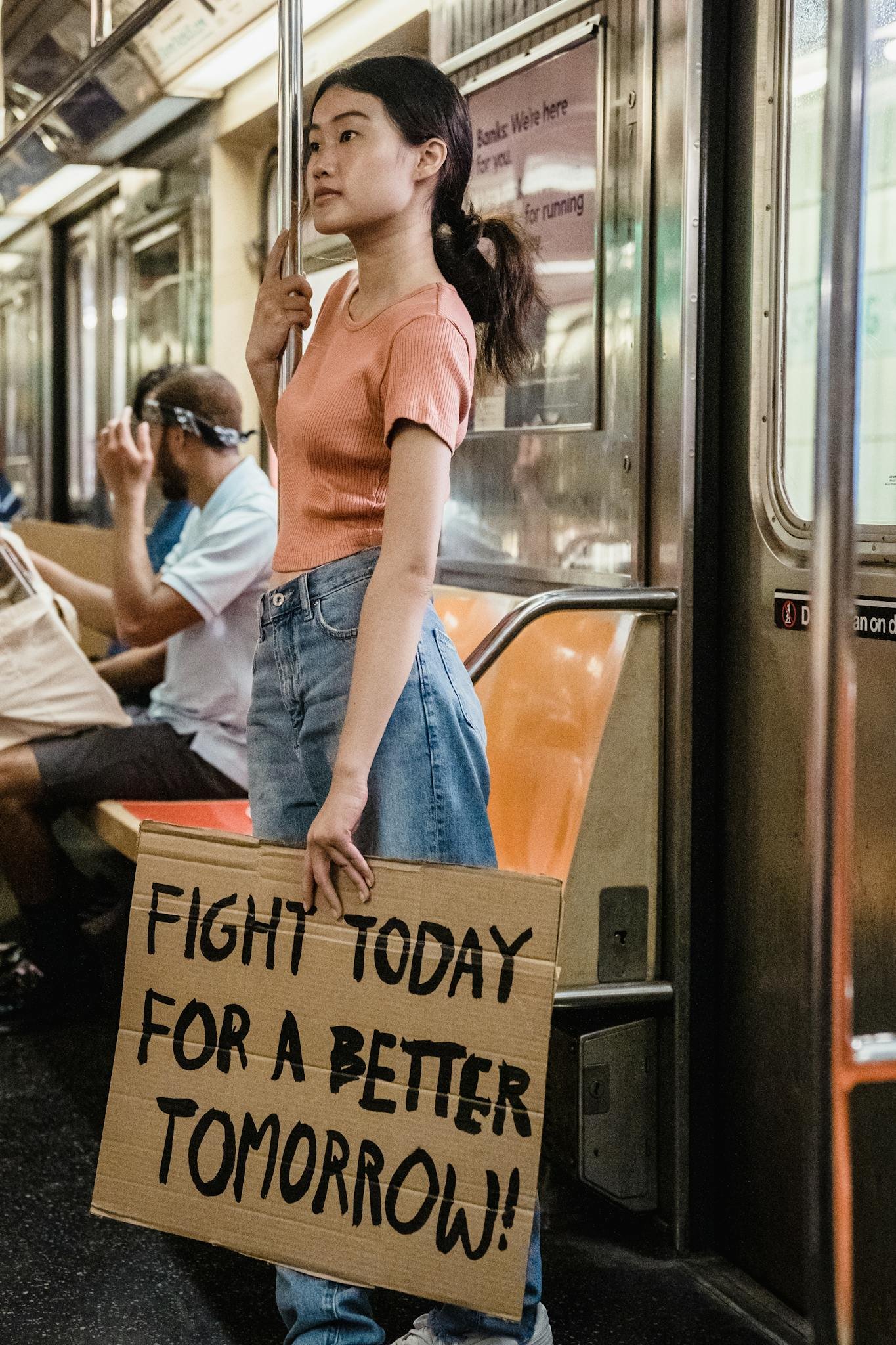 Woman holding a protest sign advocating for change on a subway train.